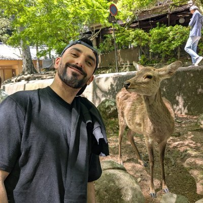 Eduardo smiling beside a deer outdoors